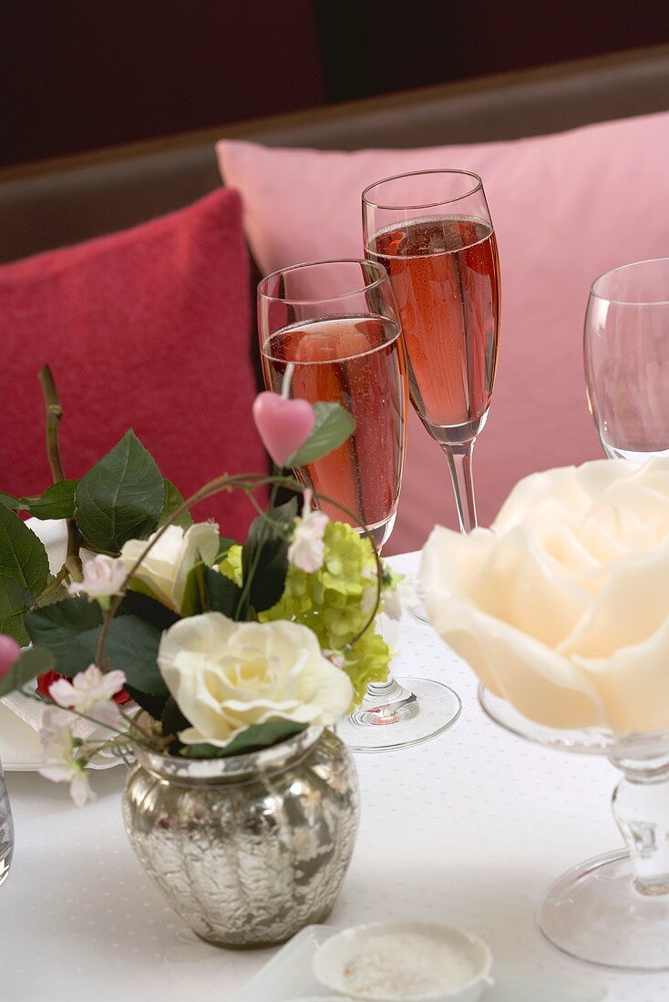 Zwei Gläser rosefarbener Champagner auf romantischem Tisch