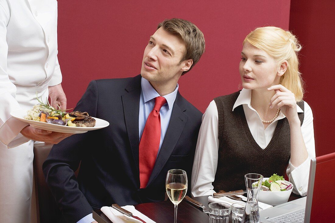 Waiter serving lunch to business people