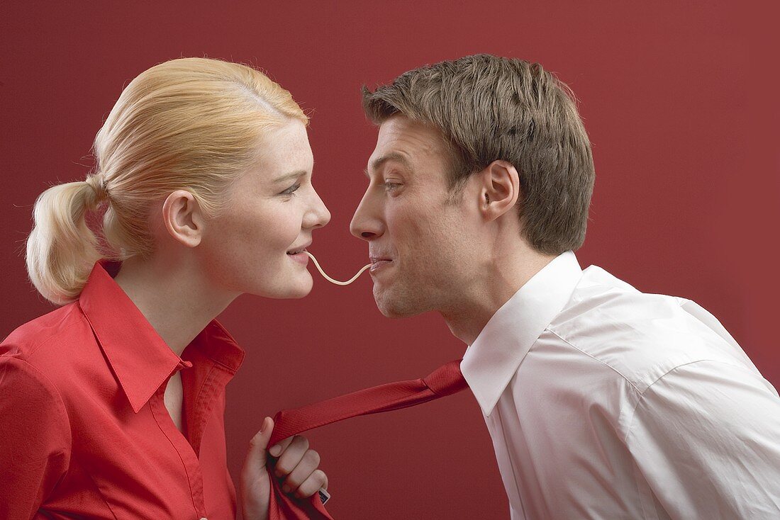 Couple eating a strand of spaghetti from both ends