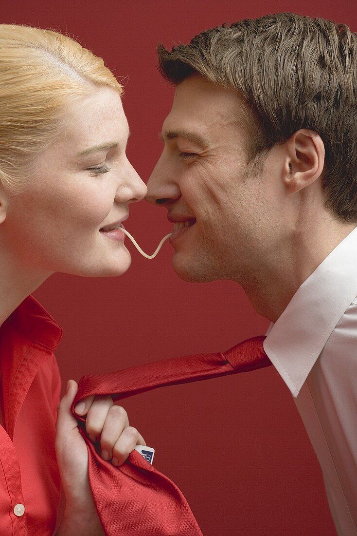 Couple eating a strand of spaghetti from both ends