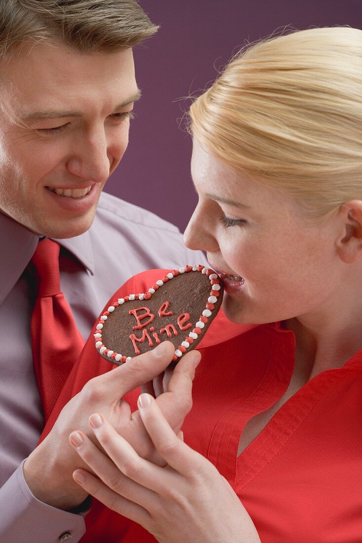 Woman tasting chocolate heart with the words Be Mine