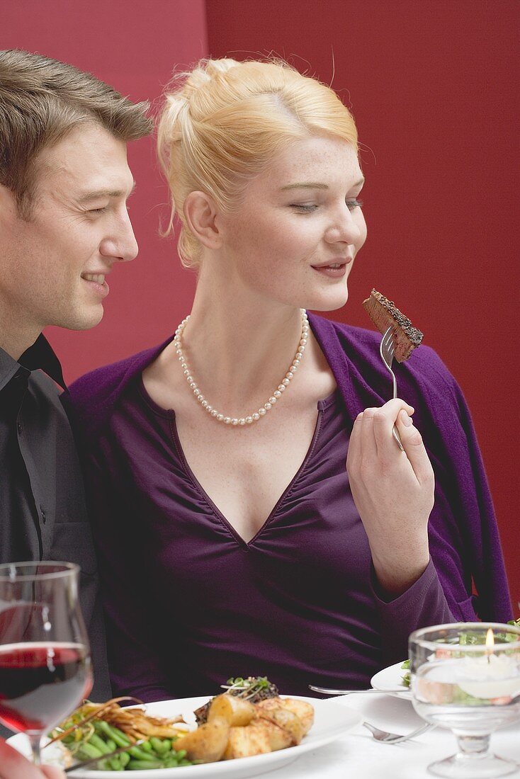 Woman looking at piece of beef steak on fork