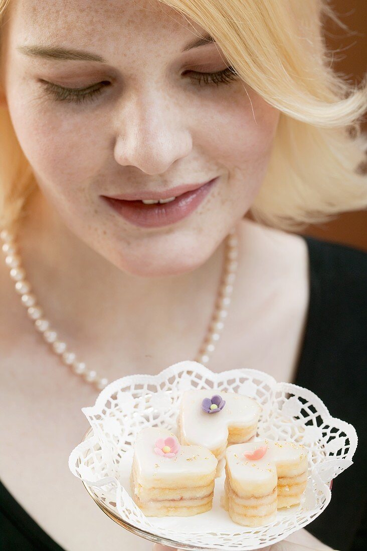 Woman holding dish containing three petit fours