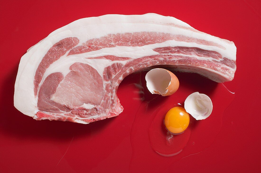 Bio-Schweinekotelett und aufgeschlagenes Ei