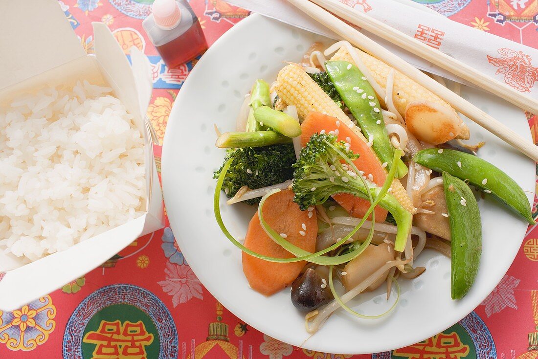 Stir-fried vegetables with soy sauce, rice in take-away container