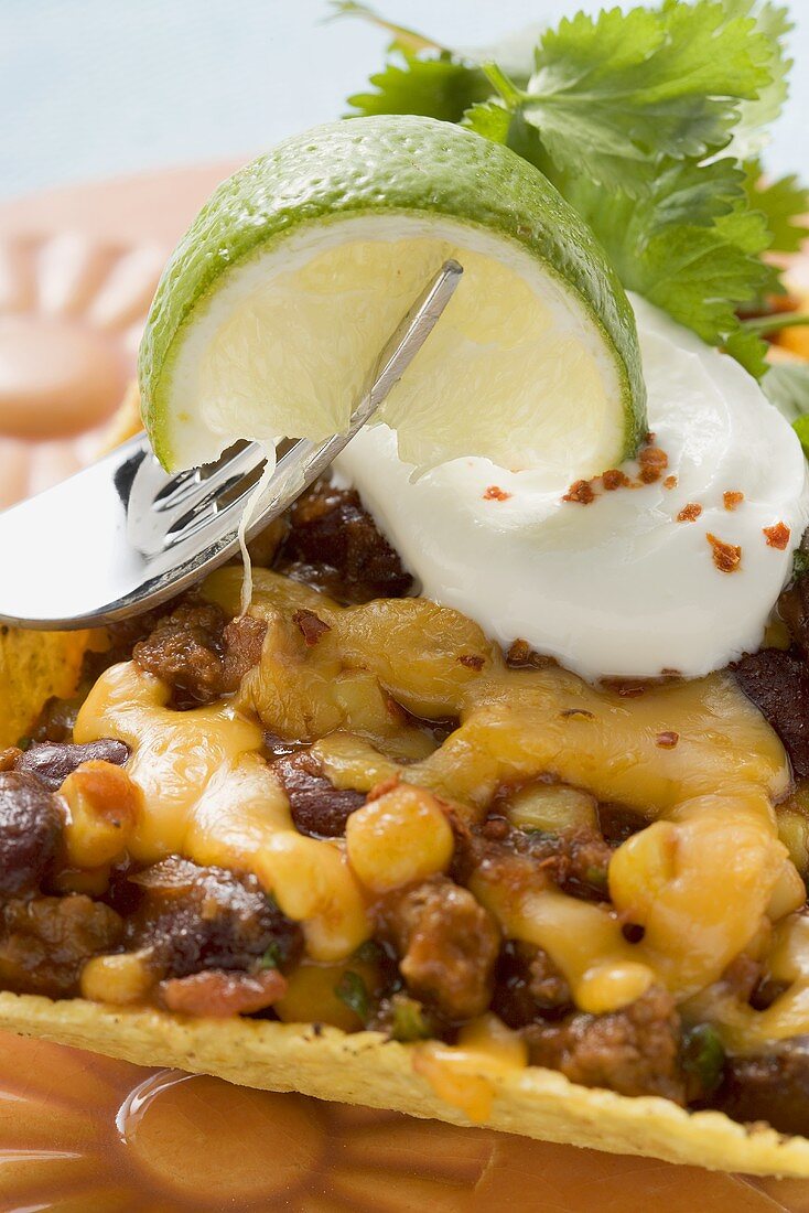 Chili con carne in corn shell, lime on fork (Mexico)