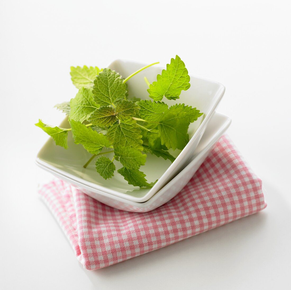 Lemon balm in a small dish on a checked cloth