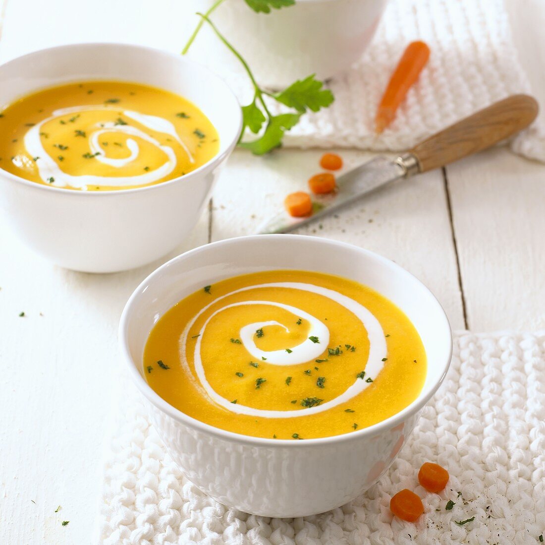 Two bowls of carrot soup with swirls of cream