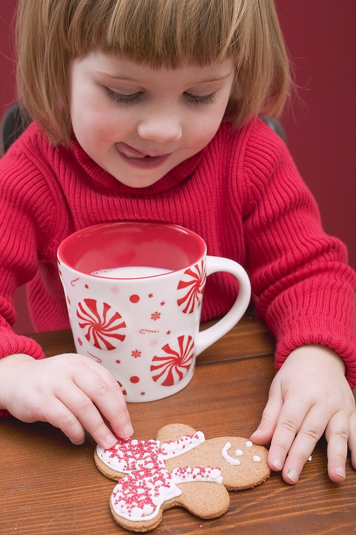 Kleines Mädchen mit Tasse Milch und Lebkuchenfigur