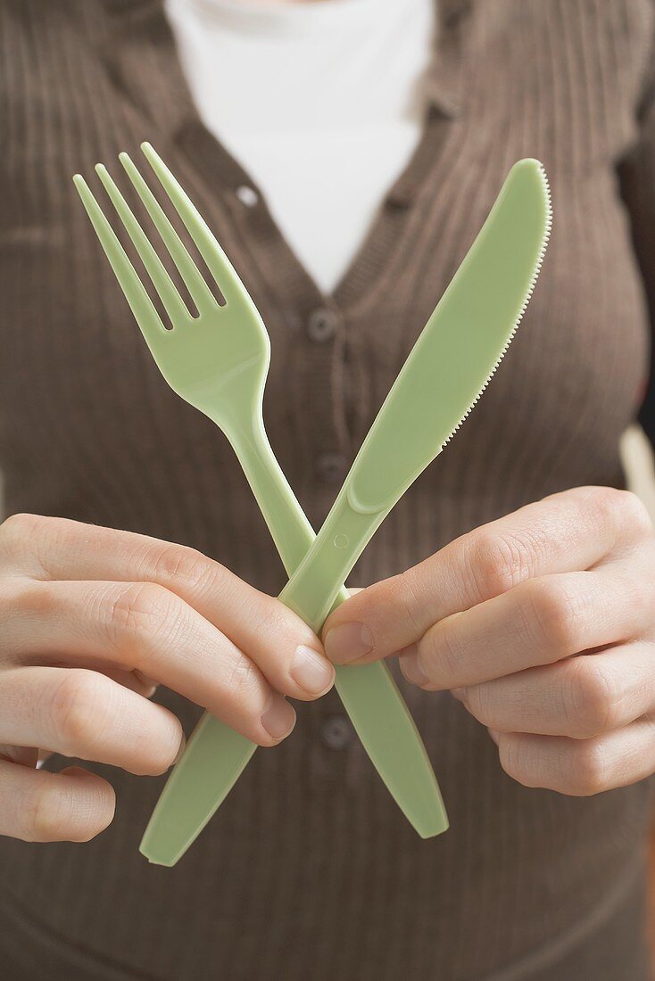 Woman holding plastic knife and fork