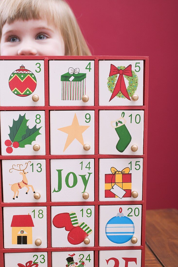 Kleines Mädchen hinter Adventskalender