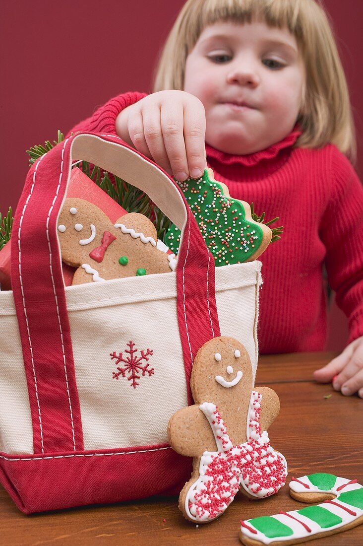 Kleines Mädchen nimmt Weihnachtsplätzchen aus Tasche