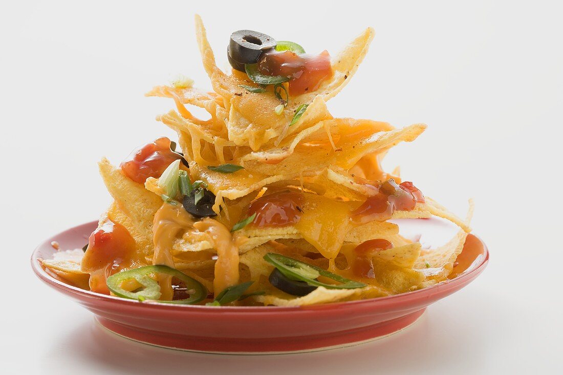 Nachos with cheese, olives, chilli rings & ketchup on plate