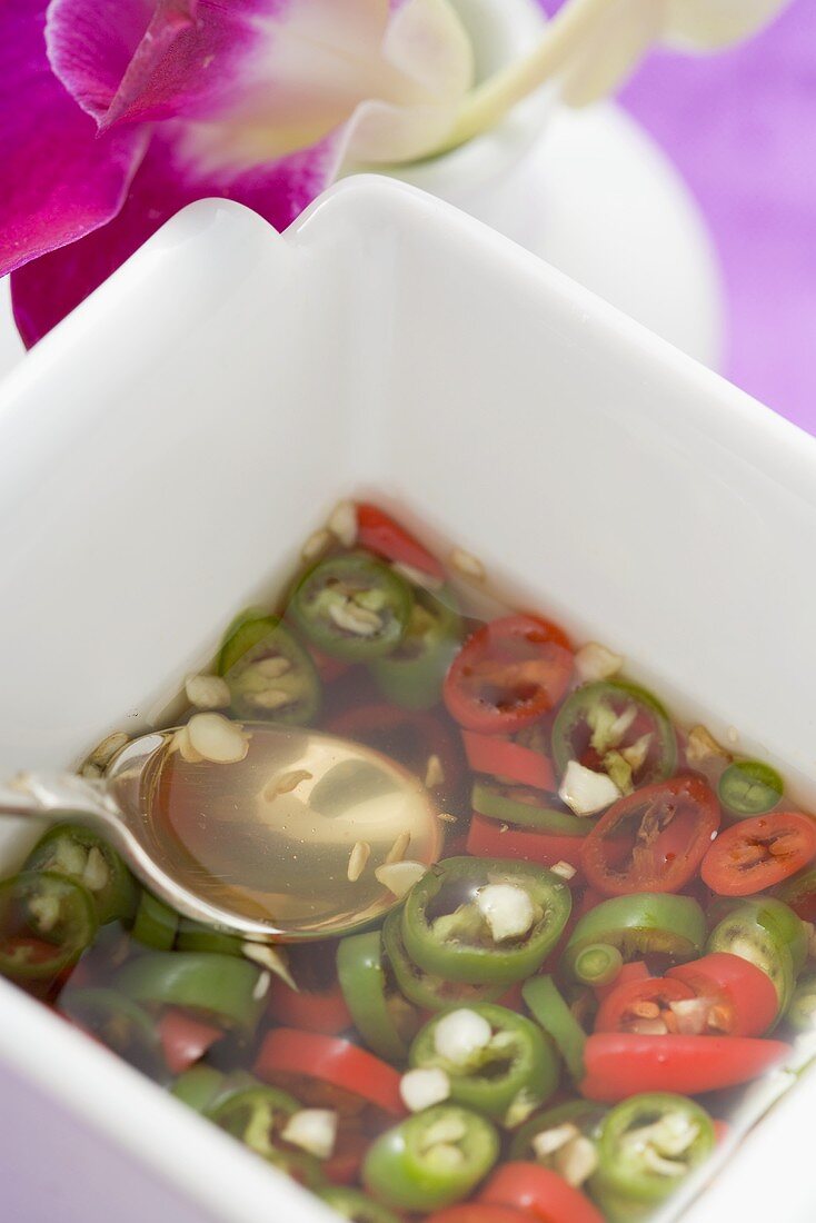 Scharfe Chilisauce im Schälchen mit Löffel (Asien)