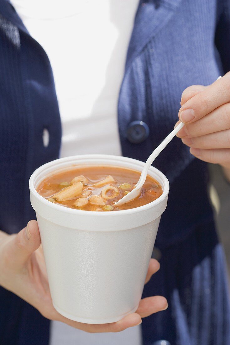 Frau isst Minestrone aus einem Becher