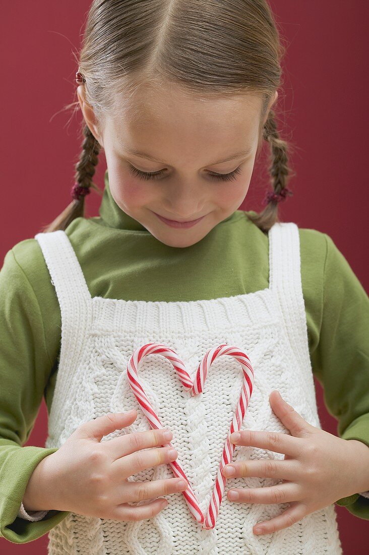 Kleines Mädchen hält Herz aus Zuckerstangen