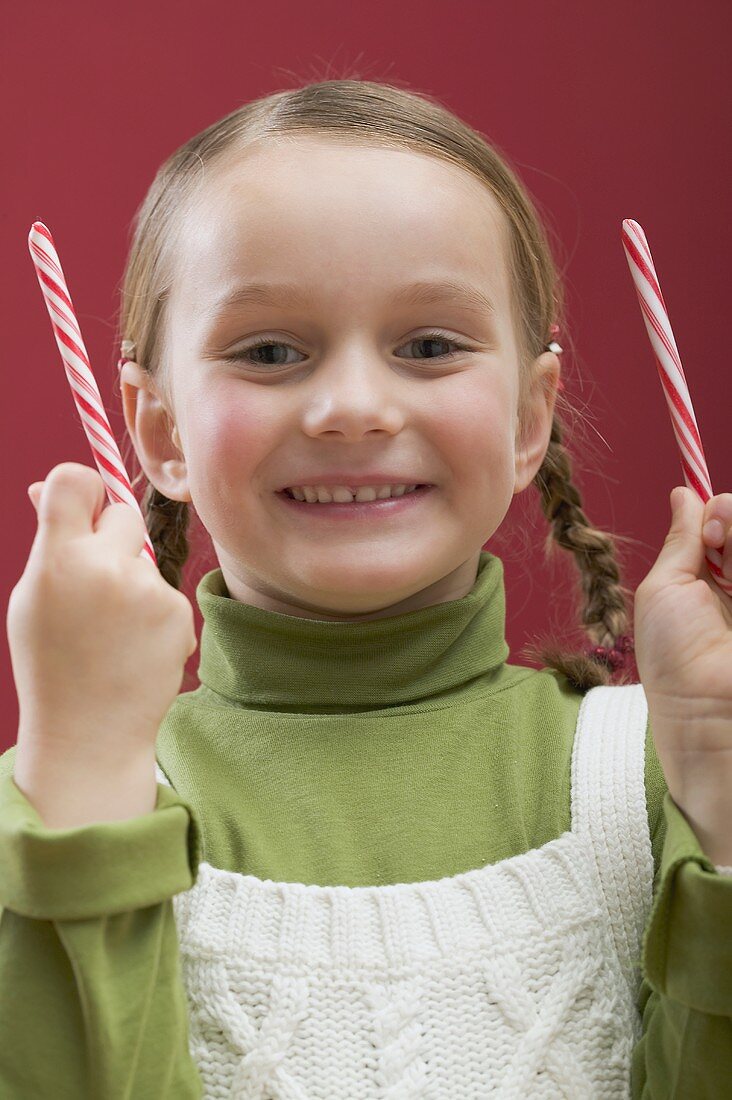 Kleines Mädchen hält zwei Zuckerstangen