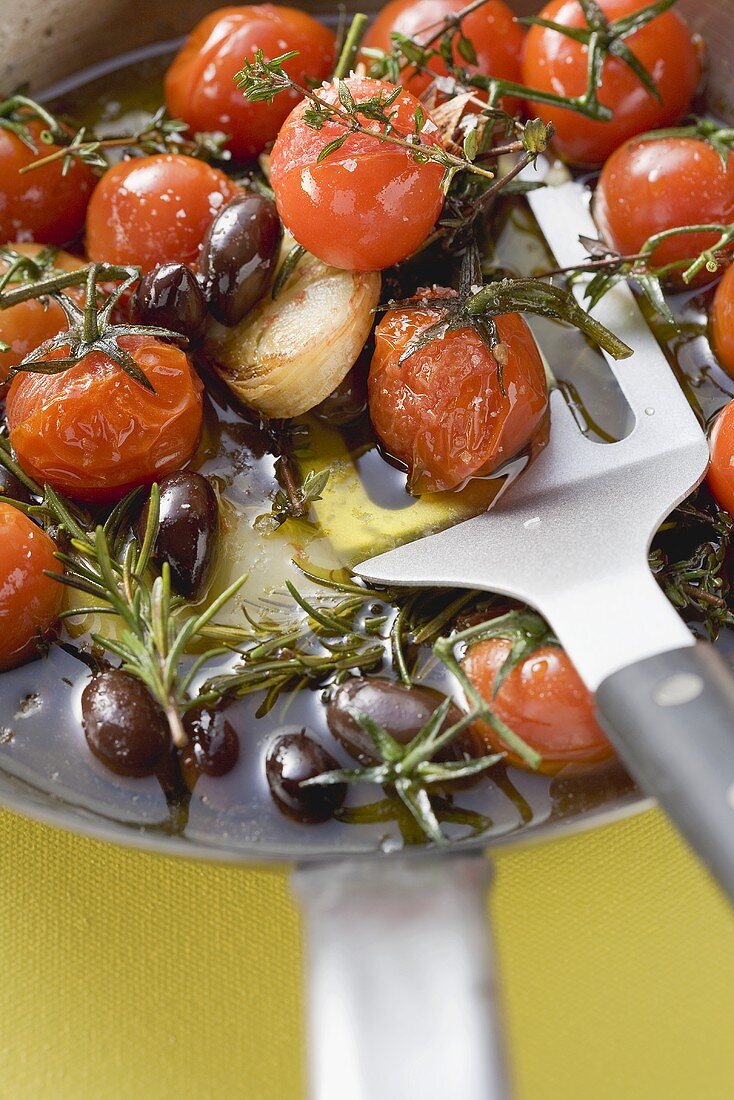 Gebratene Kirschtomaten mit Knoblauch und Oliven in Pfanne