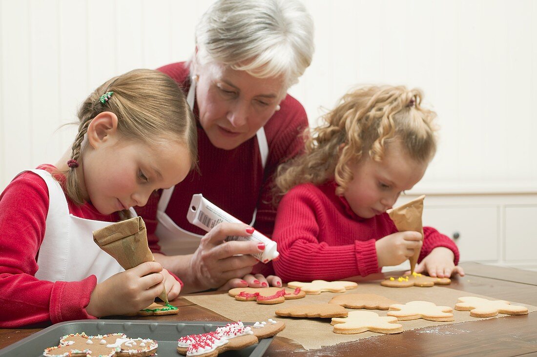 Grossmutter und zwei Enkeltöchter verzieren Weihnachtskekse