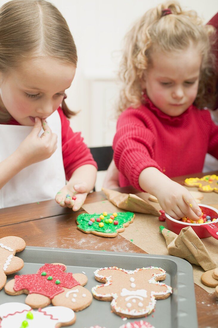 Two small girls decorating Christmas biscuits