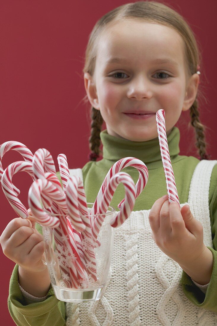 Small girl holding glass full of candy canes