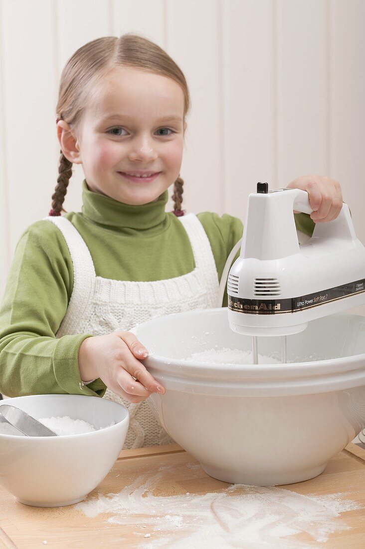Small girl using electric mixer