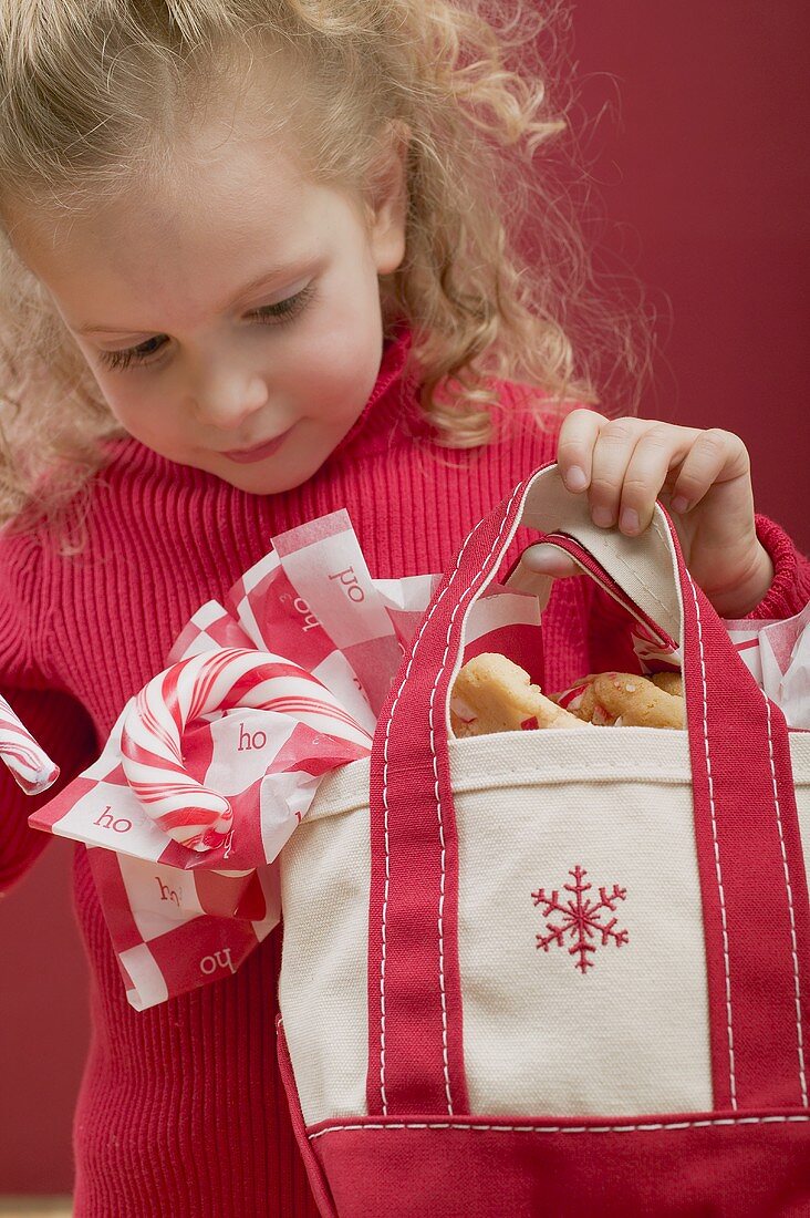 Small girl holding bag of candy canes and biscuits