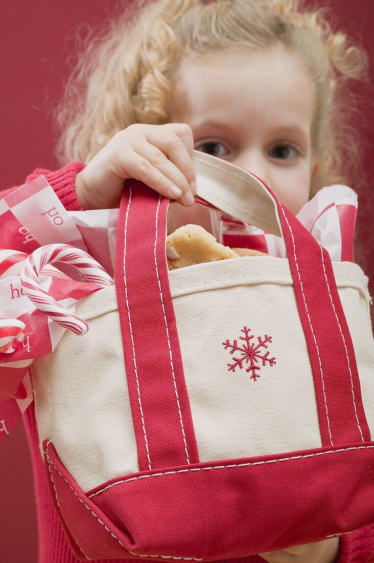 Small girl holding bag of candy canes and biscuits