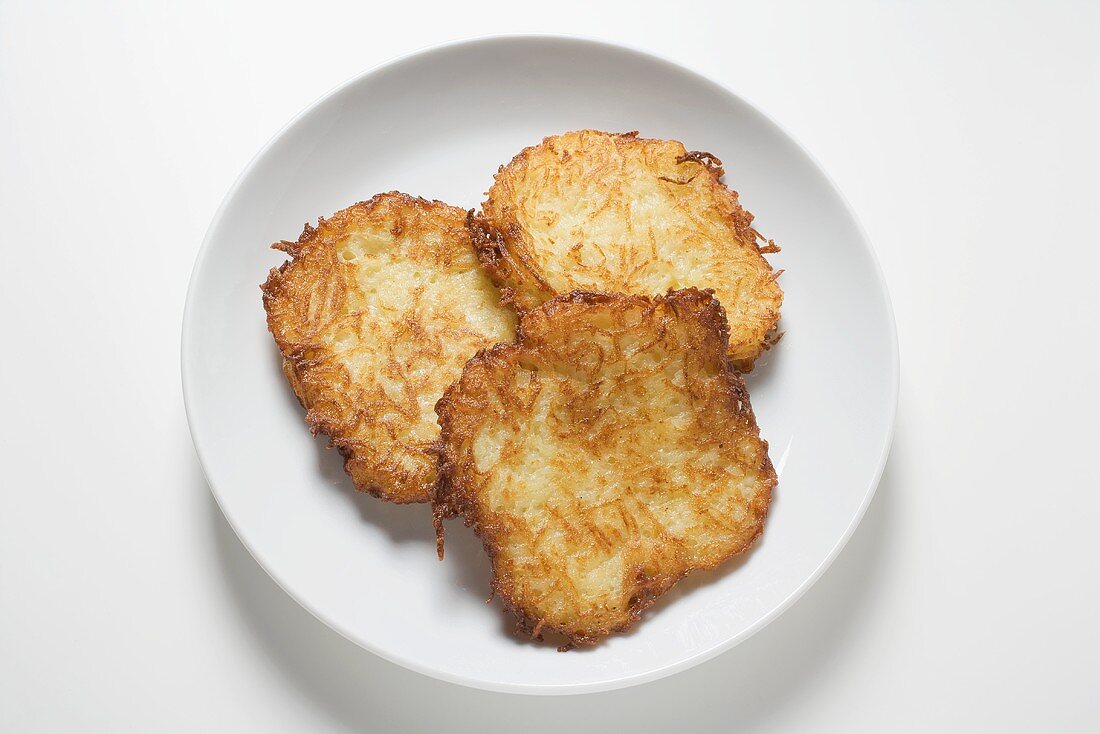 Three potato rostis on plate (overhead view)