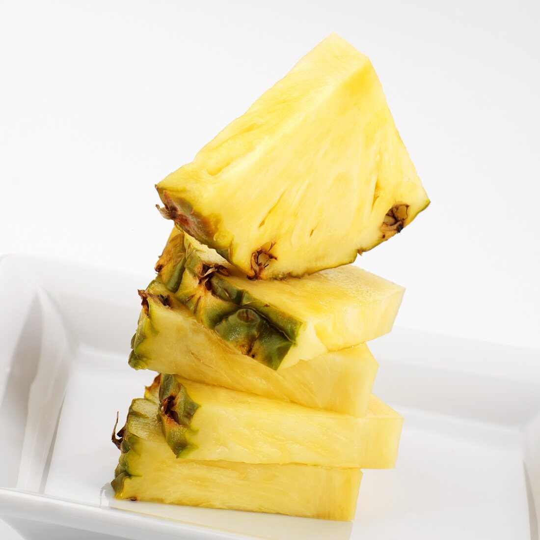 Pineapple quarters, stacked in white dish
