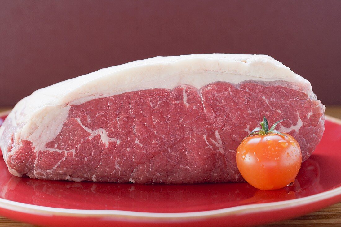 Frisches Rindfleisch und Kirschtomate auf rotem Teller