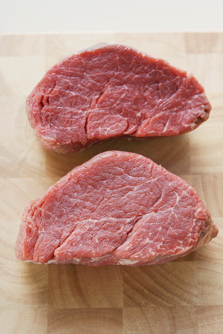 Two beef medallions on chopping board