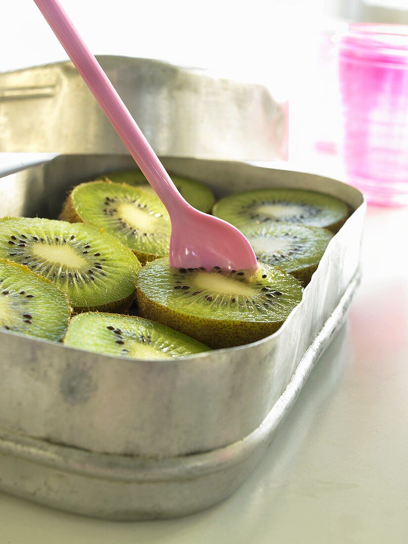 Lunch box containing fresh kiwi fruit with plastic spoon