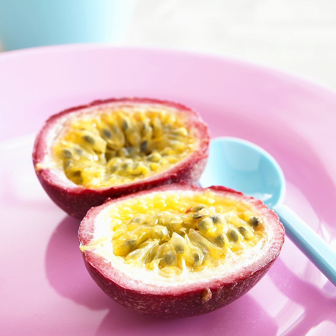 Passion fruit, halved, on plate with spoon