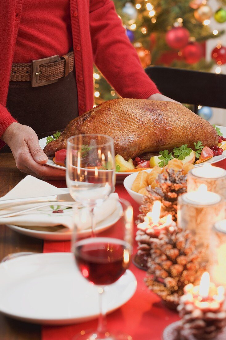 Frau serviert gebratene Ente zu Weihnachten