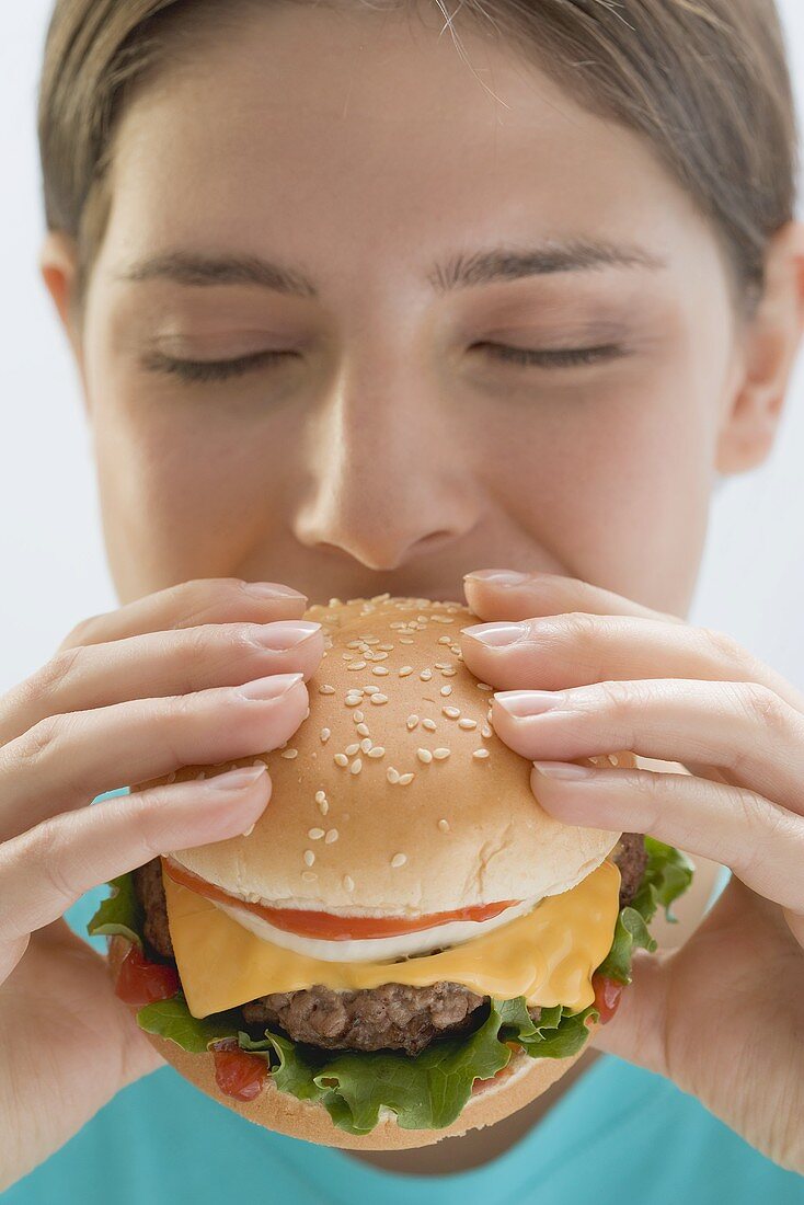 Young woman biting into cheeseburger