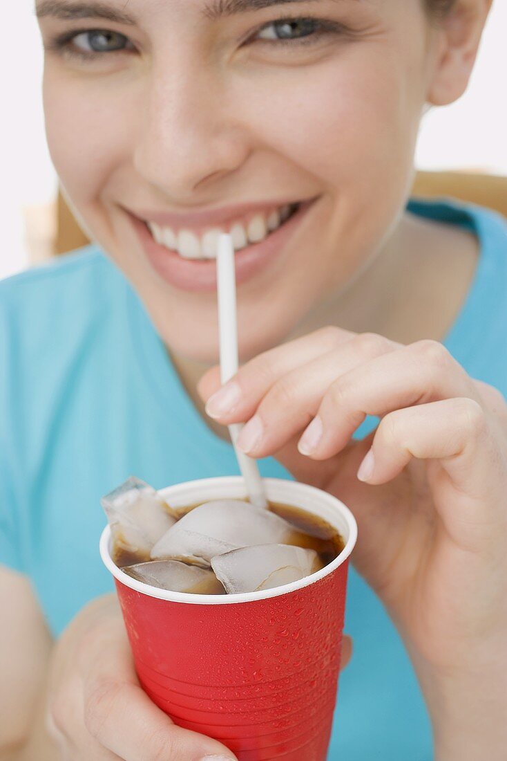 Junge Frau trinkt Cola mit Strohhalm
