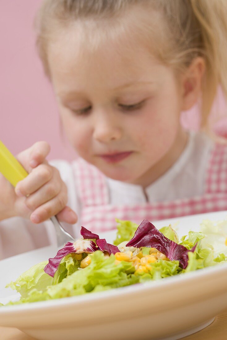 Kleines Mädchen isst Blattsalat mit Mais
