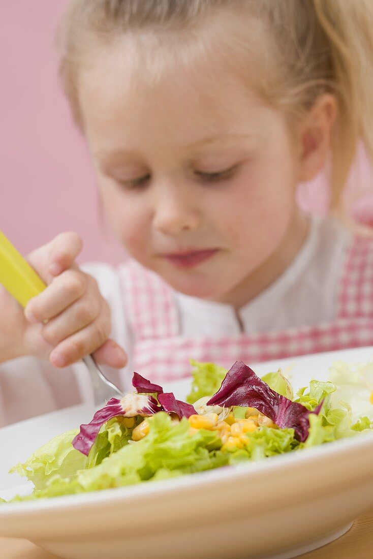 Little girl eating salad leaves with sweetcorn