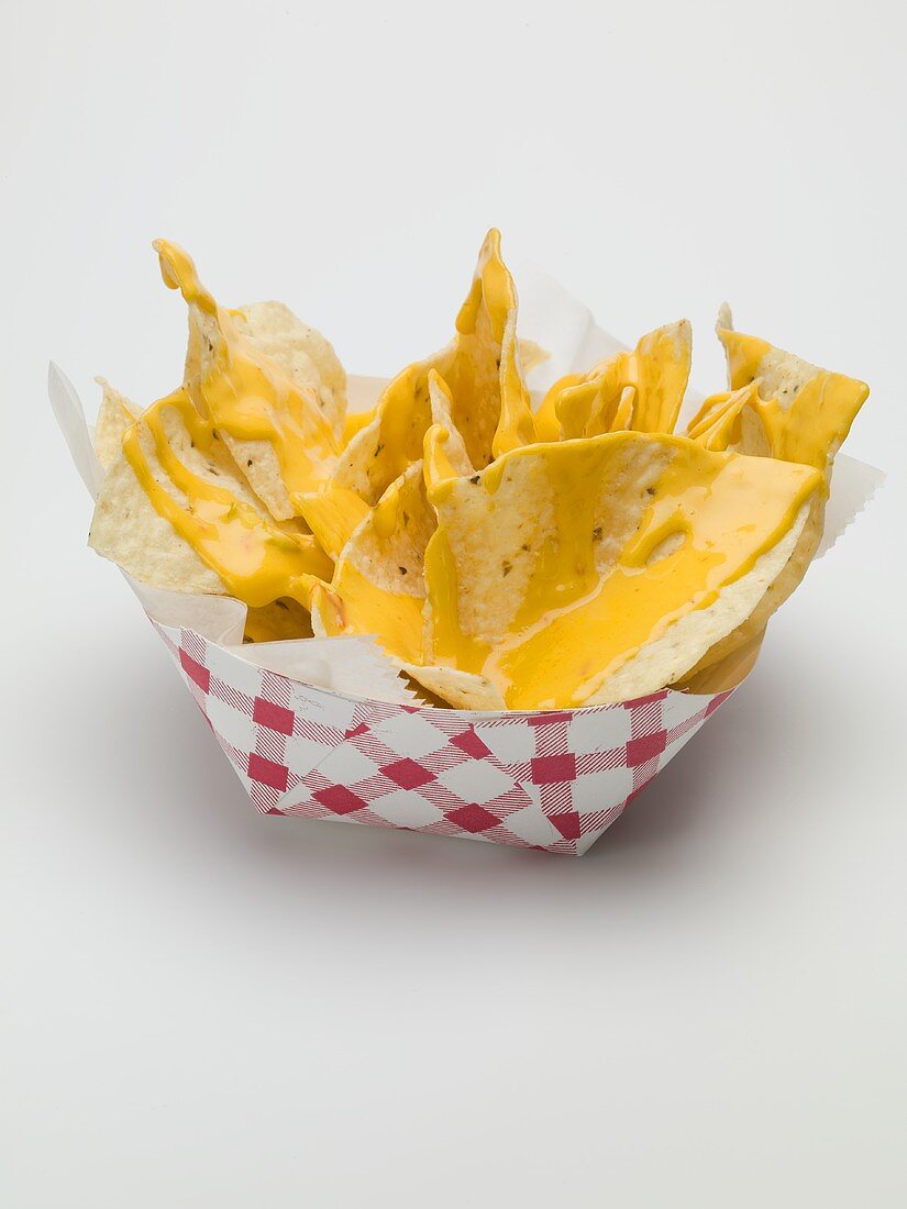 Nachos with cheese sauce in paper dish