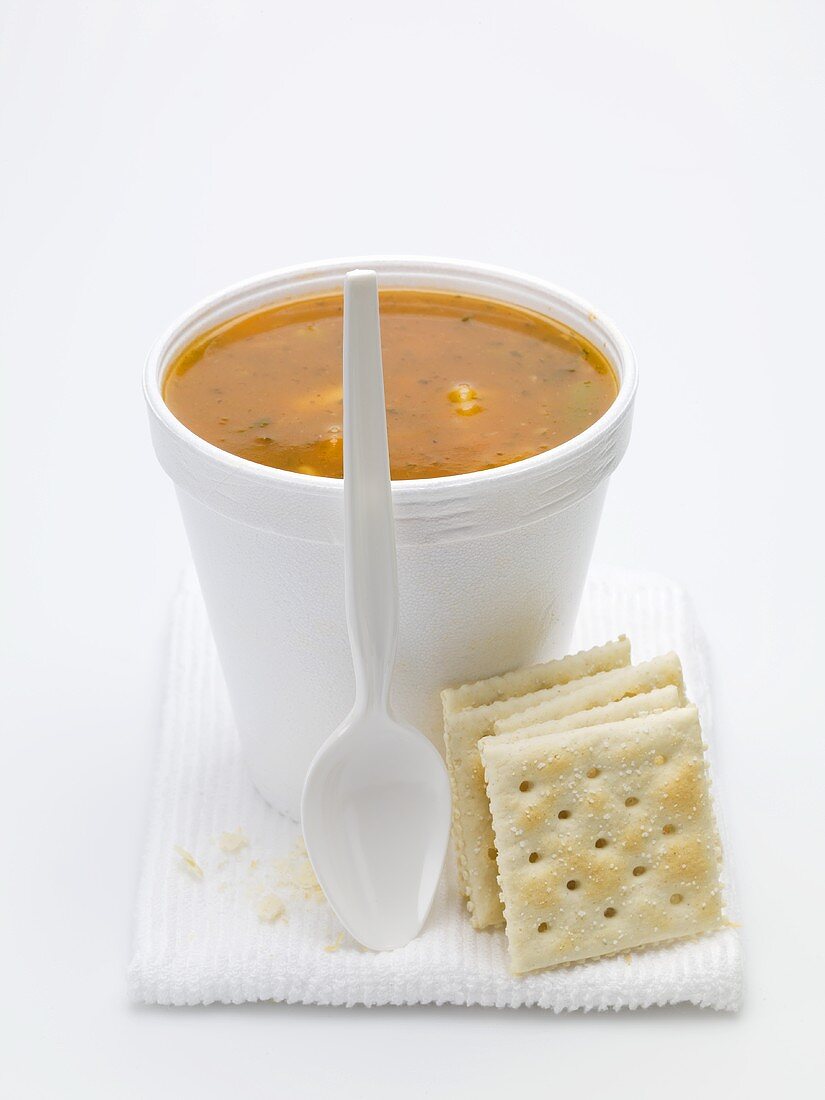 Tomato and vegetable soup in polystyrene cup, crackers