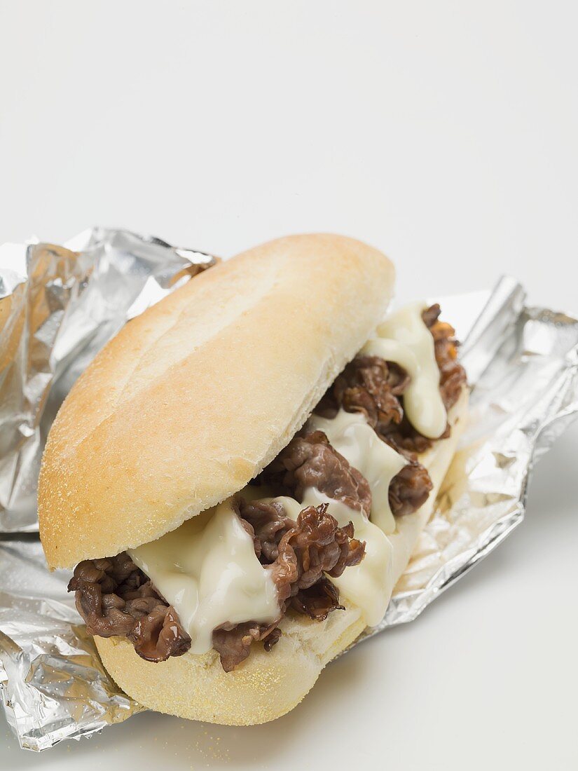 Shredded beef sandwich with melted cheese on aluminium foil