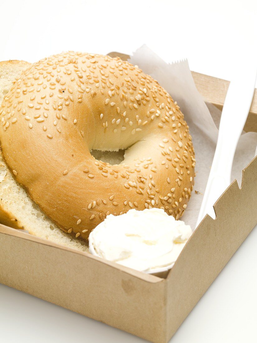 Sesame bagel with crème fraîche in a cardboard box