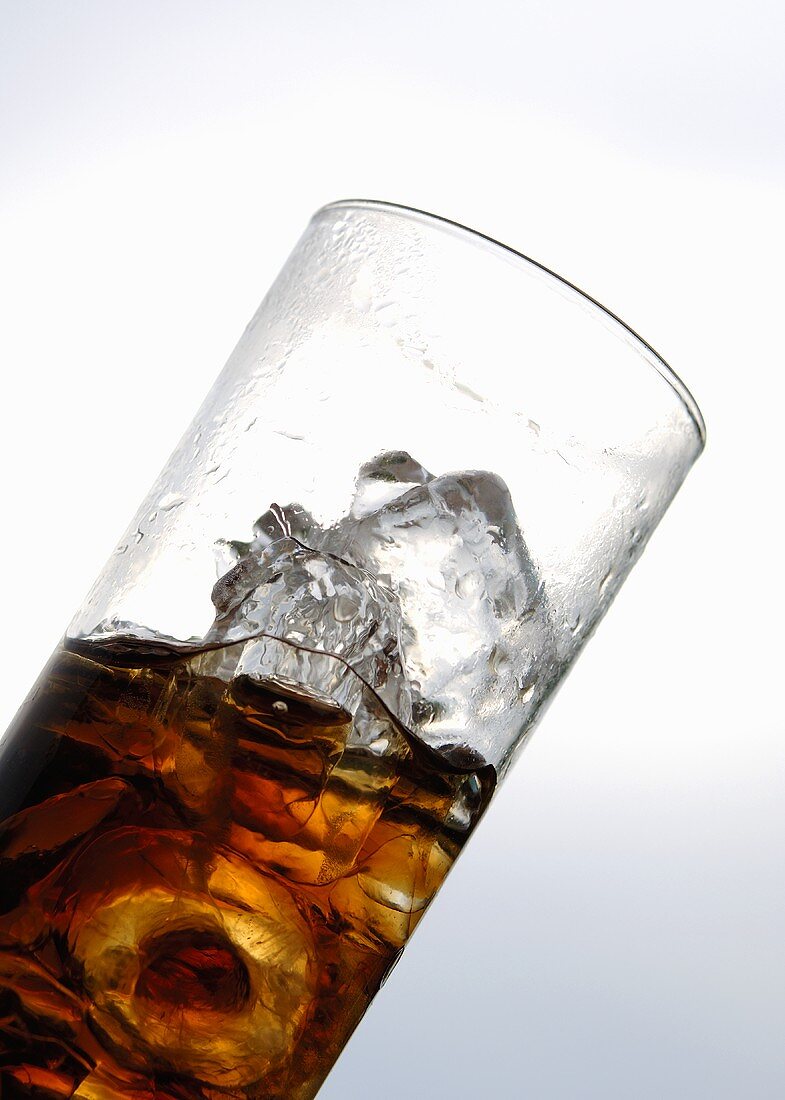 Cola mit Eiswürfeln im Glas (Schräglage)