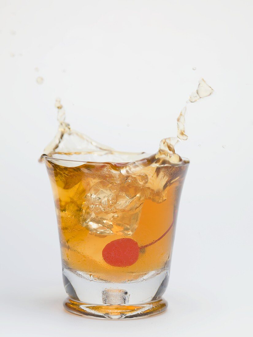 Ice cube falling into a glass of Manhattan