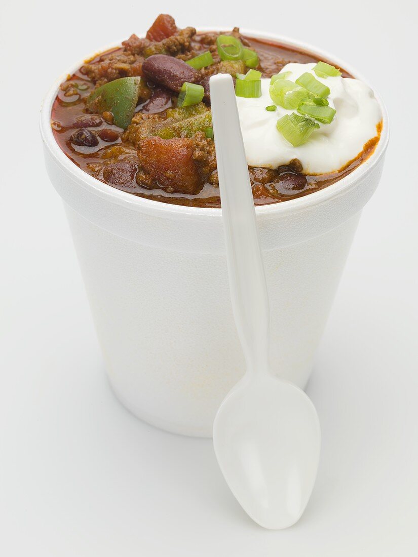 Chili con carne & sour cream in polystyrene cup, plastic spoon