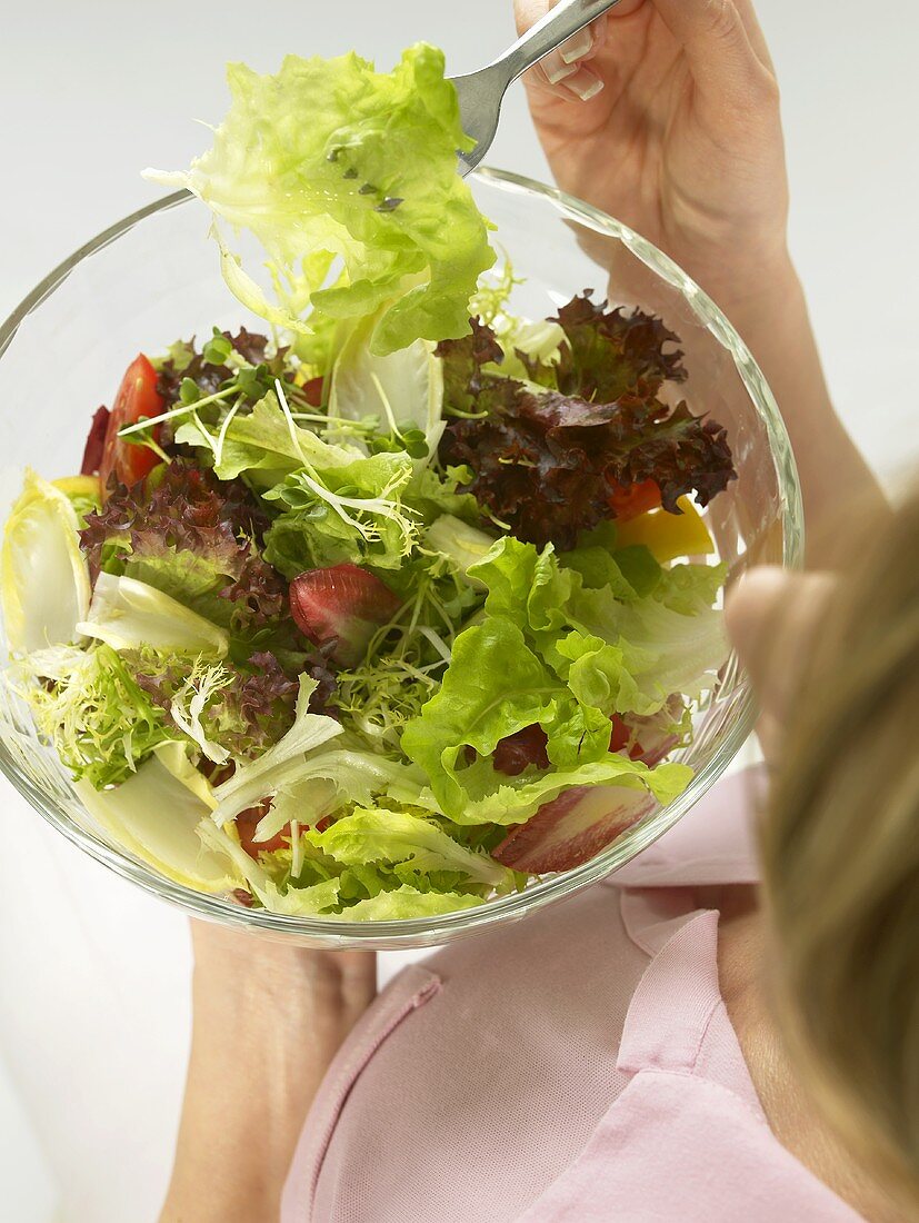 Frau isst Blattsalat aus Glasschüssel