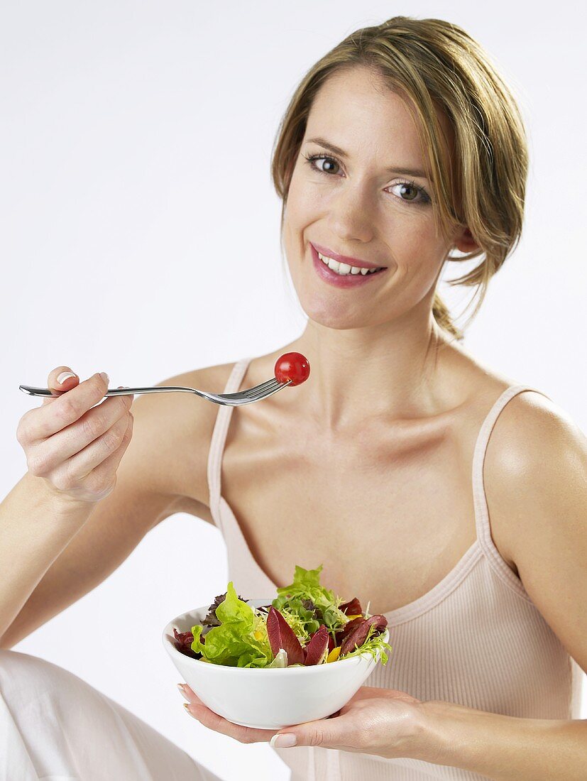 Frau isst Blattsalat mit Kirschtomaten
