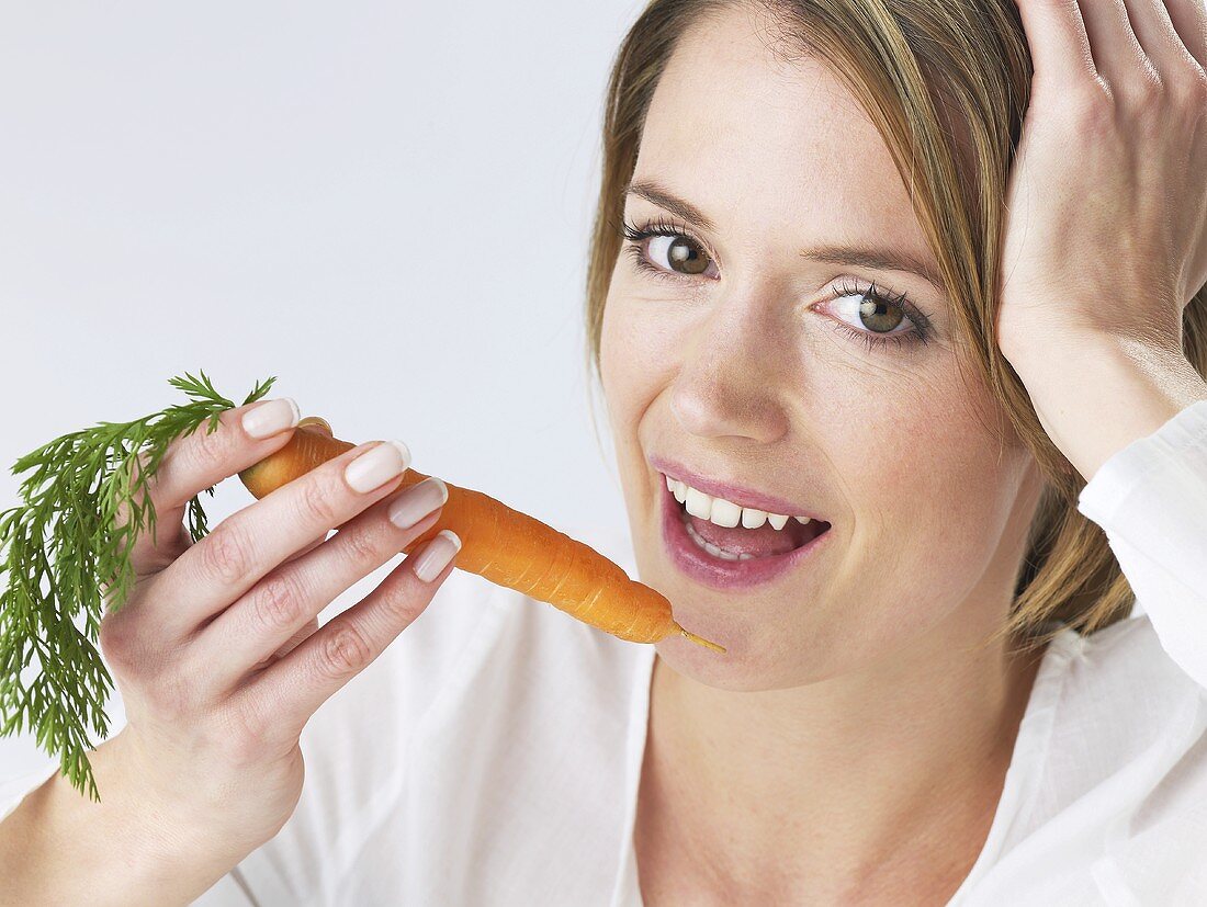 Woman about to bite into a carrot