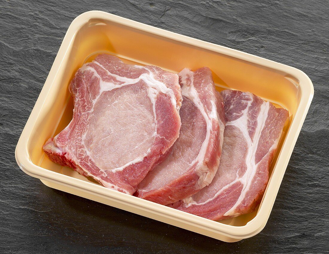 Three pork chops in plastic container